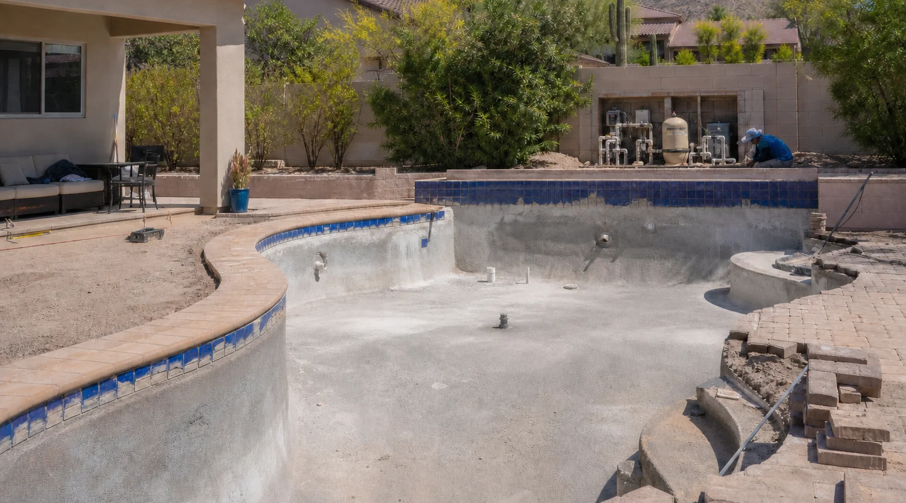 Existing Arizona pool under coordinated renovation with the drained shell, waterline tile, equipment pad, and deck work visible together.
