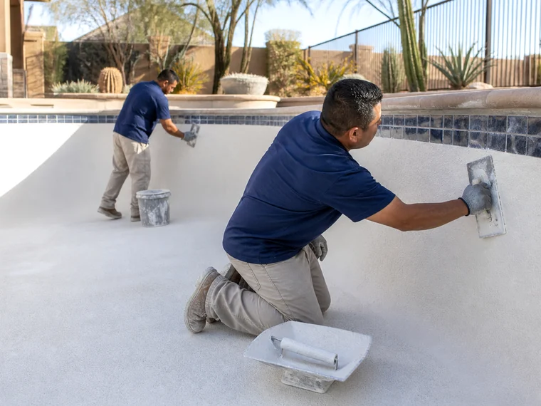 Drained residential and commercial pool undergoing interior surface preparation and tile replacement during a remodeling project.